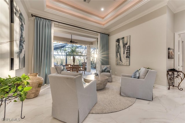 living area with marble finish floor, ceiling fan, a tray ceiling, and crown molding