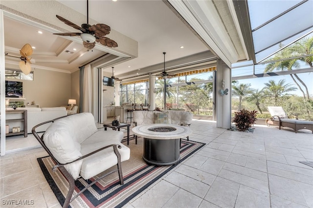 view of patio featuring a lanai, visible vents, a ceiling fan, and an outdoor living space with a fire pit