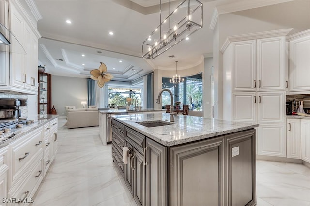 kitchen with marble finish floor, a kitchen island with sink, ornamental molding, and a sink