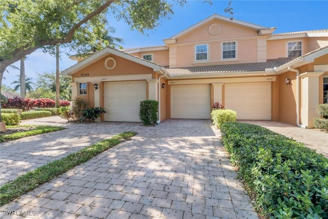 view of front of house with a tiled roof, decorative driveway, and stucco siding