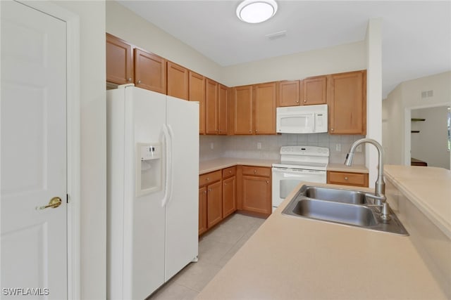 kitchen featuring white appliances, light tile patterned floors, a sink, light countertops, and tasteful backsplash