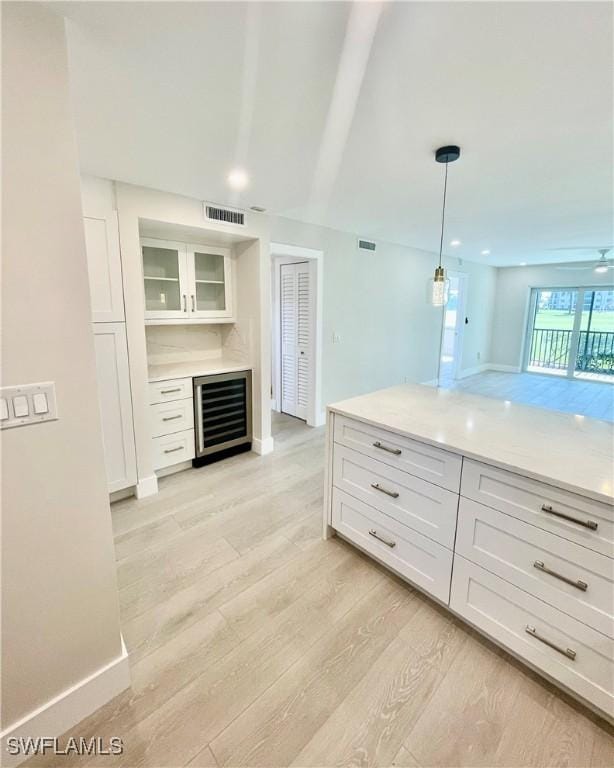 kitchen featuring wine cooler, visible vents, white cabinets, light countertops, and light wood finished floors