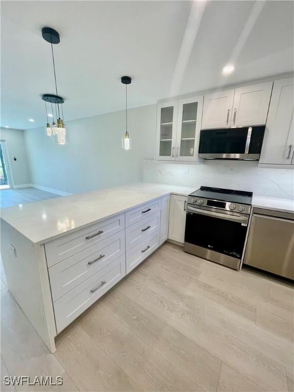 kitchen featuring appliances with stainless steel finishes, glass insert cabinets, white cabinets, light wood-type flooring, and a peninsula