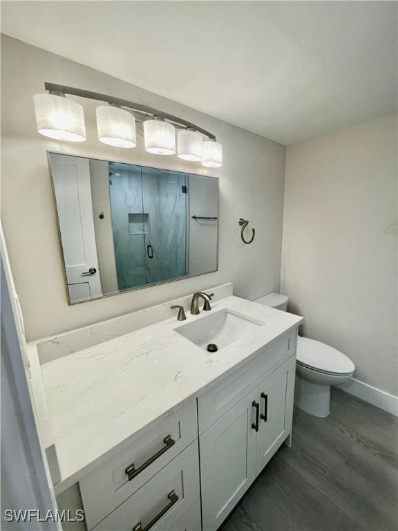 full bathroom with toilet, wood finished floors, vanity, baseboards, and a shower with door