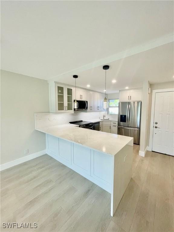 kitchen with light wood finished floors, white cabinetry, a peninsula, and stainless steel appliances