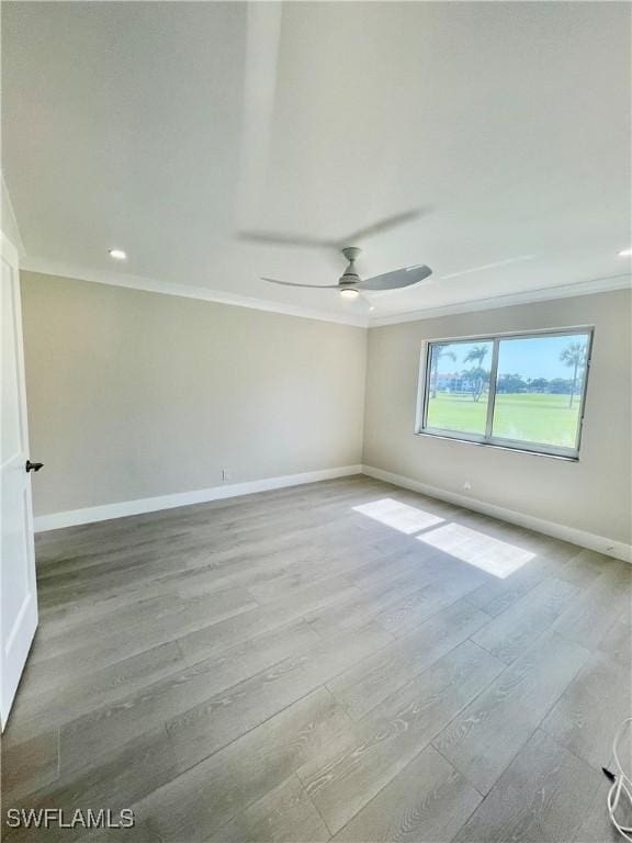 empty room with a ceiling fan, baseboards, crown molding, and wood finished floors