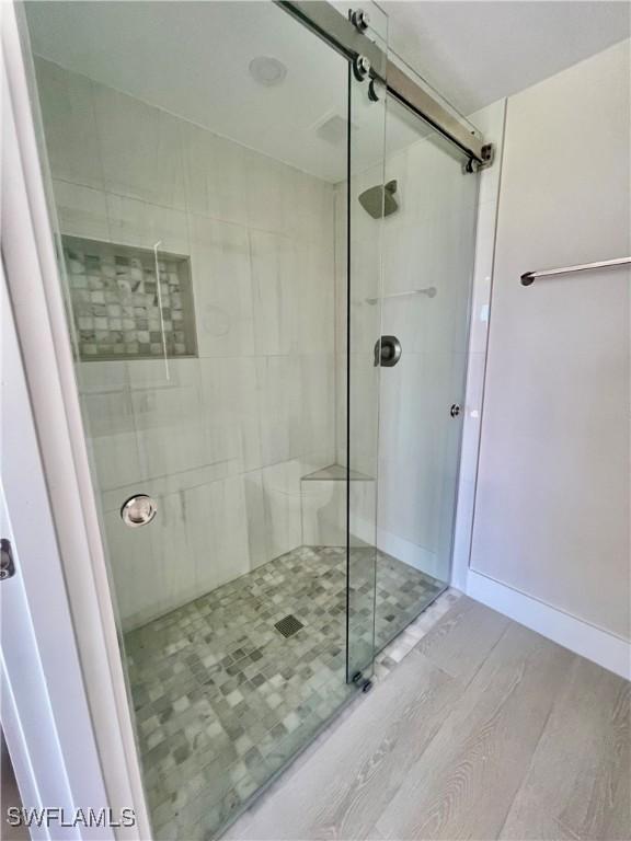 full bathroom featuring a shower stall, baseboards, and wood finished floors