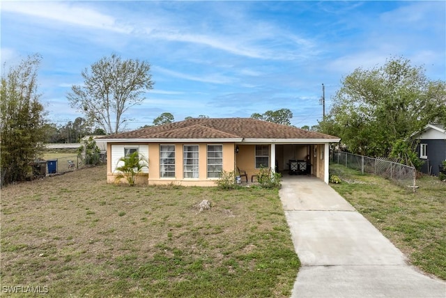 ranch-style house featuring an attached carport, fence, concrete driveway, stucco siding, and a front lawn