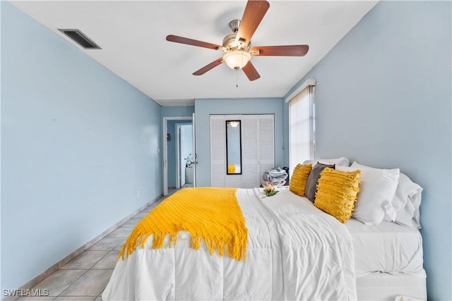 bedroom featuring light tile patterned floors, ceiling fan, visible vents, and a closet