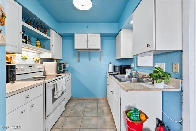 kitchen with white electric stove, light countertops, a sink, and white cabinetry