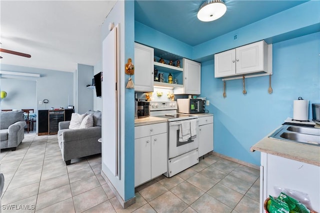 kitchen with white range with electric cooktop, open floor plan, light tile patterned flooring, white cabinets, and a sink