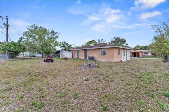 exterior space featuring an outbuilding, cooling unit, fence, a storage unit, and a front lawn