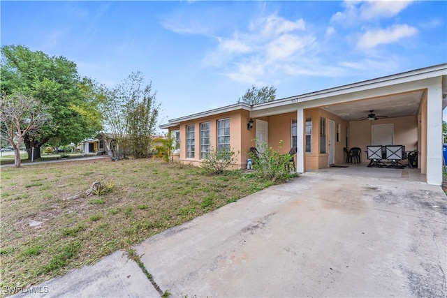 exterior space with a lawn, an attached carport, concrete driveway, and stucco siding