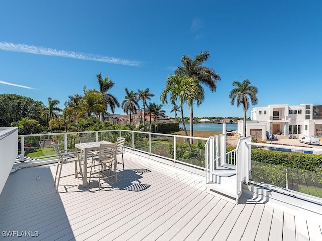 wooden deck with outdoor dining area and a water view