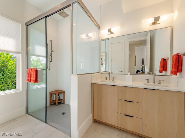 full bath with a sink, baseboards, a shower with shower door, and double vanity