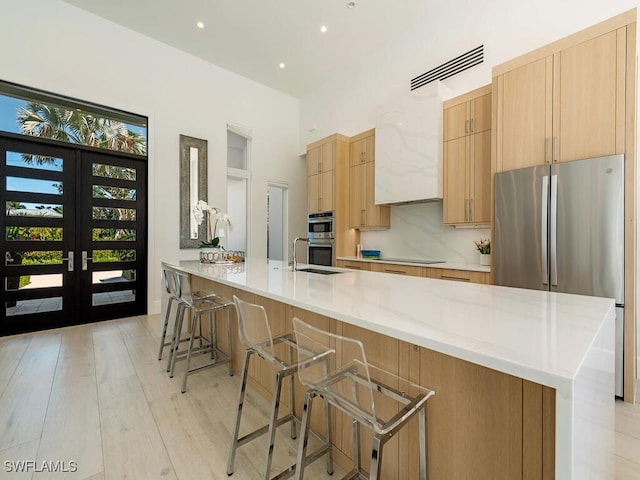 kitchen featuring light wood finished floors, visible vents, french doors, stainless steel appliances, and a sink