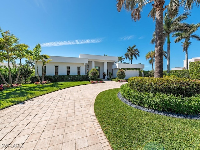 view of front of property featuring a front lawn, decorative driveway, and stucco siding