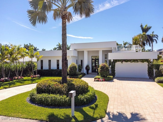 contemporary home featuring stucco siding, an attached garage, and decorative driveway