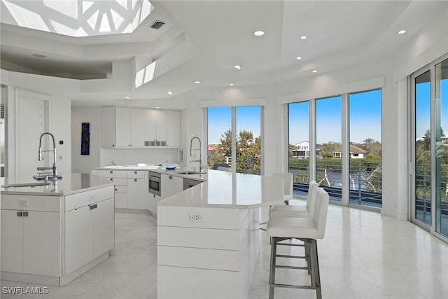 kitchen with a sink, visible vents, a peninsula, and white cabinetry