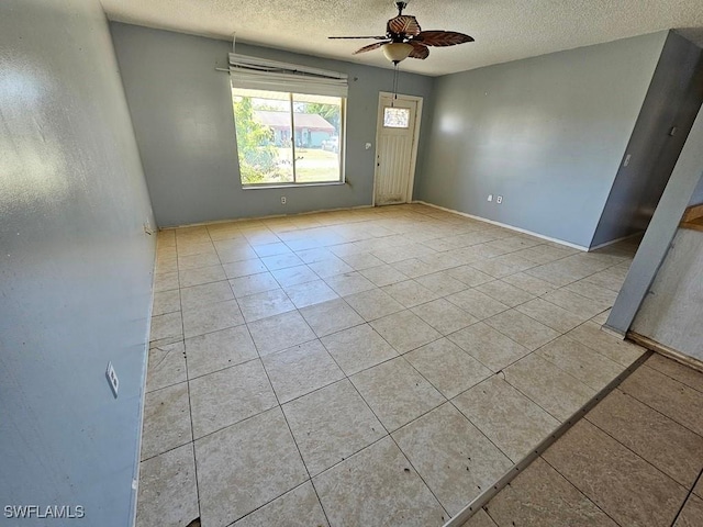 tiled empty room with a textured ceiling and a ceiling fan