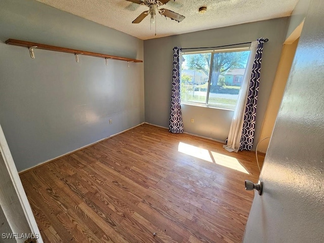 empty room featuring a textured ceiling, ceiling fan, and wood finished floors