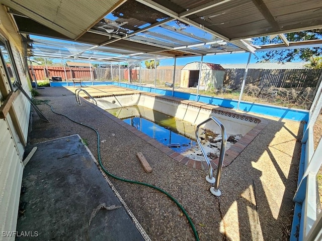 view of pool with glass enclosure, a fenced backyard, a fenced in pool, and a patio