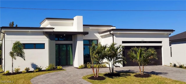 contemporary home with stucco siding, an attached garage, and decorative driveway