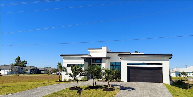 view of front of property with stucco siding, decorative driveway, an attached garage, and a front yard