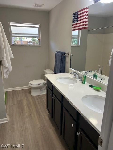 bathroom with baseboards, visible vents, a sink, and wood finished floors