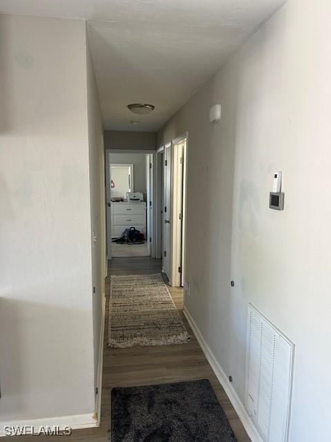 corridor with visible vents, baseboards, and wood finished floors