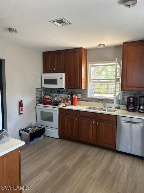 kitchen featuring white appliances, light wood-style flooring, a sink, and visible vents