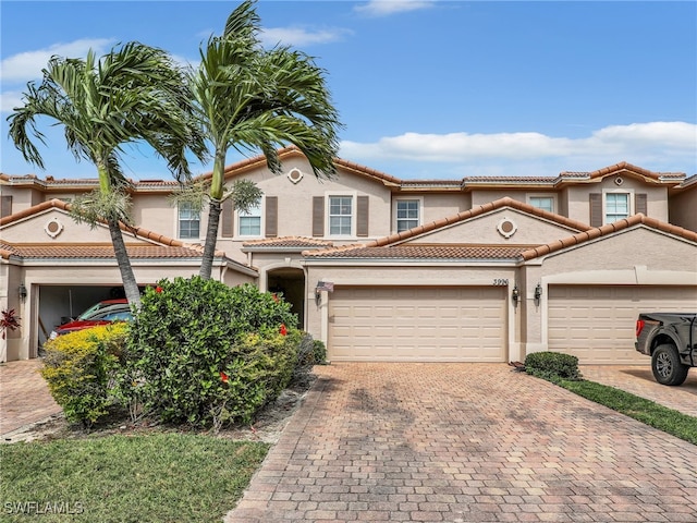 view of front of property with decorative driveway, a tiled roof, an attached garage, and stucco siding