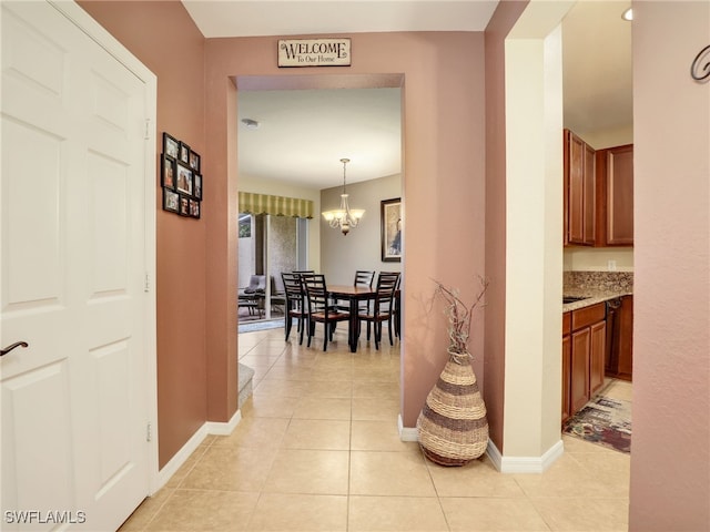 hallway with baseboards, a chandelier, and light tile patterned flooring