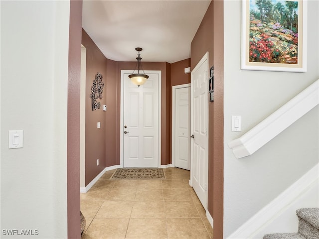 interior space with stairway, baseboards, and light tile patterned floors