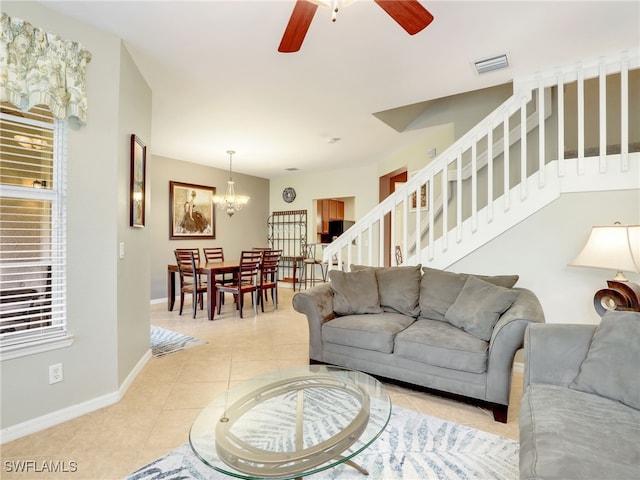 living room featuring light tile patterned floors, ceiling fan with notable chandelier, visible vents, baseboards, and stairs