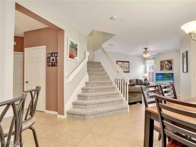 stairway with ceiling fan, baseboards, and tile patterned floors