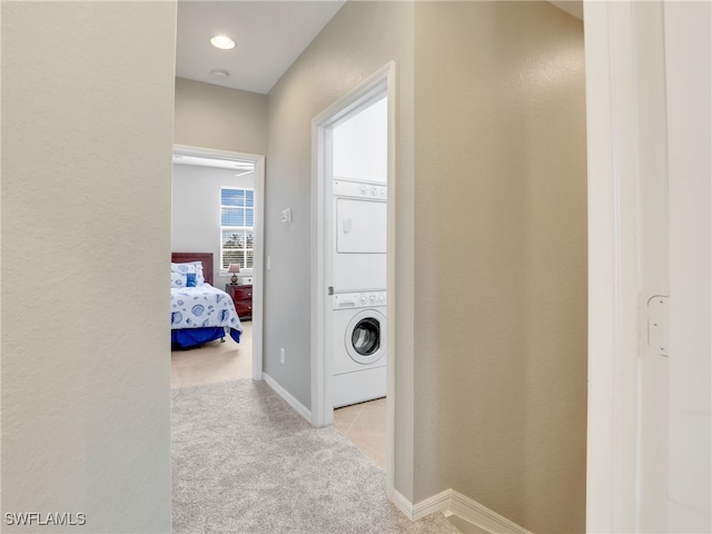 hallway featuring carpet floors, stacked washer / drying machine, and baseboards