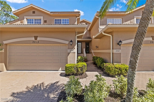 view of front of property with stucco siding, decorative driveway, a garage, and a tile roof