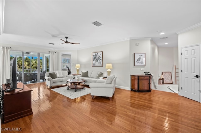 living area with visible vents, light wood-type flooring, baseboards, and ornamental molding