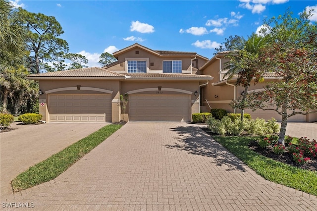 mediterranean / spanish-style home with a tiled roof, decorative driveway, and stucco siding