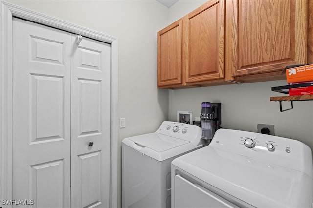 washroom featuring cabinet space and washer and clothes dryer