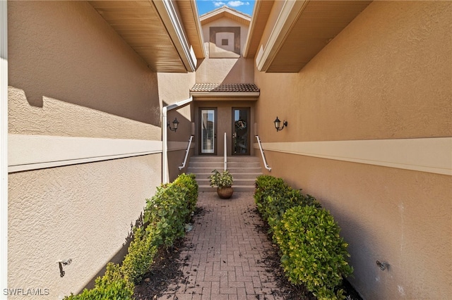 entrance to property with a tiled roof and stucco siding