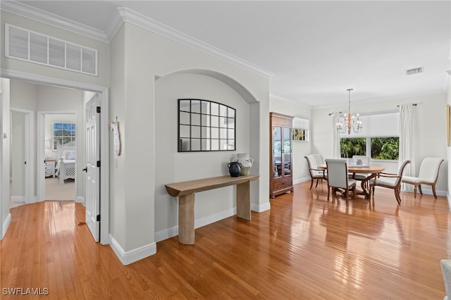 dining space featuring baseboards, visible vents, an inviting chandelier, crown molding, and light wood-type flooring