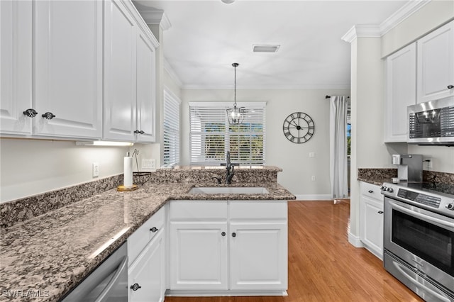 kitchen with ornamental molding, appliances with stainless steel finishes, a peninsula, white cabinetry, and a sink