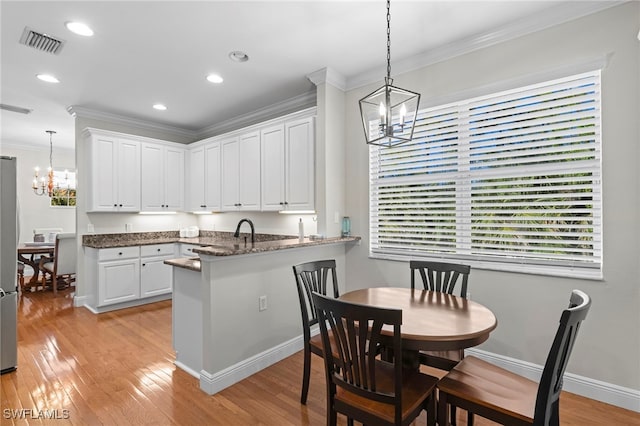 kitchen with visible vents, white cabinetry, crown molding, and an inviting chandelier