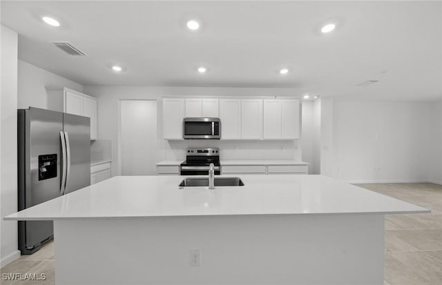 kitchen featuring a sink, visible vents, white cabinets, appliances with stainless steel finishes, and an island with sink