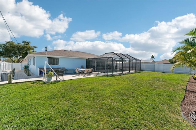 view of yard with a deck, glass enclosure, a patio, and a fenced backyard