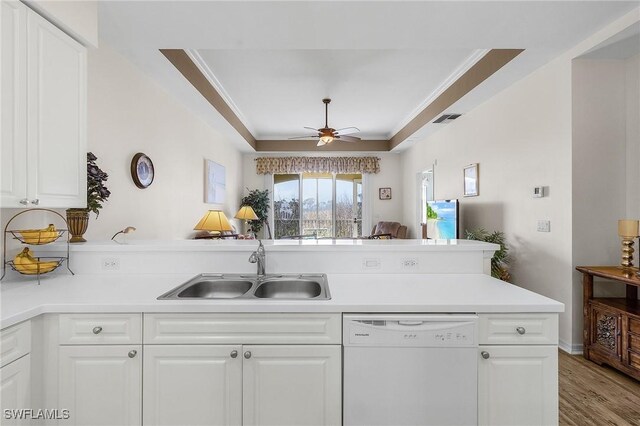 kitchen featuring visible vents, a peninsula, ornamental molding, a sink, and dishwasher