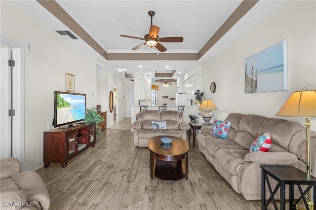 living area featuring light wood finished floors, crown molding, and ceiling fan