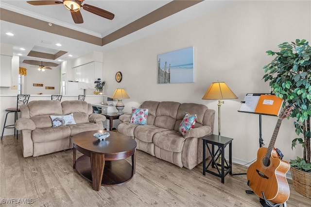 living area with a ceiling fan, light wood finished floors, recessed lighting, crown molding, and a raised ceiling